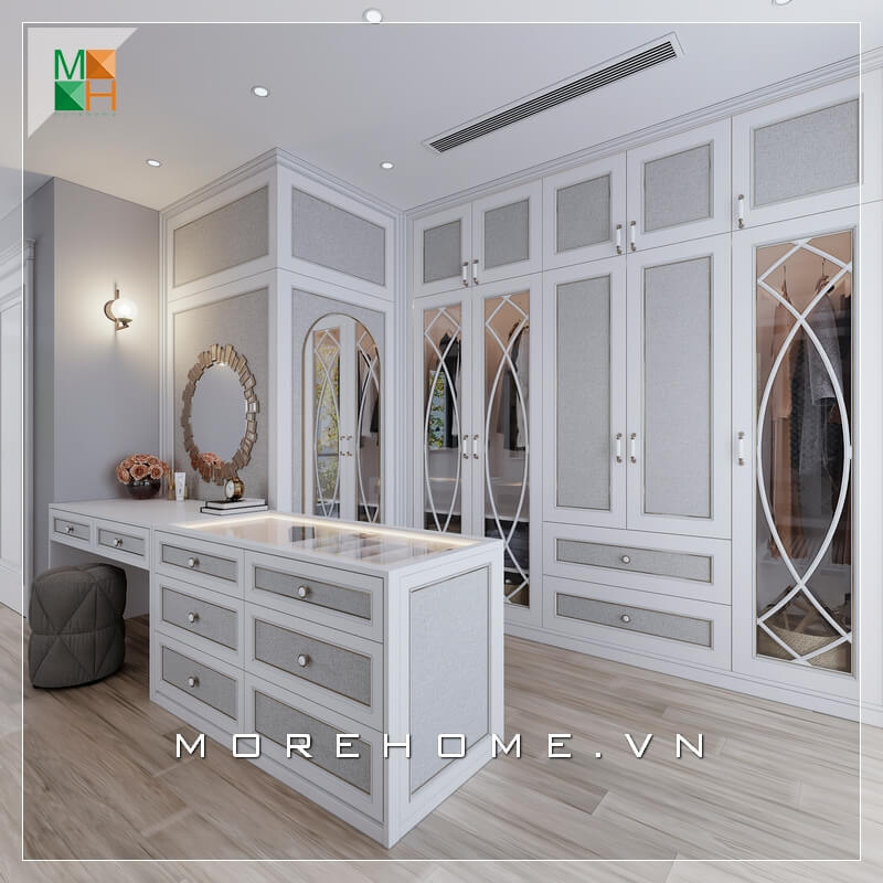 Mẫu phòng thay đồ đẹp cho biệt thự, chung cư cao cấp mang phong cách tân cổ điển, sử dụng gam màu trắng xám làm chủ đạo với hệ tủ âm tường kịch trần và đảo phụ kiện kết hợp bàn trang điểm, giúp không gian thử đồ của gia chủ trở nên gọn gàng nhưng cũng không kém phần sang trọng, đẳng cấp Thiết kế chung cư tân cổ điển